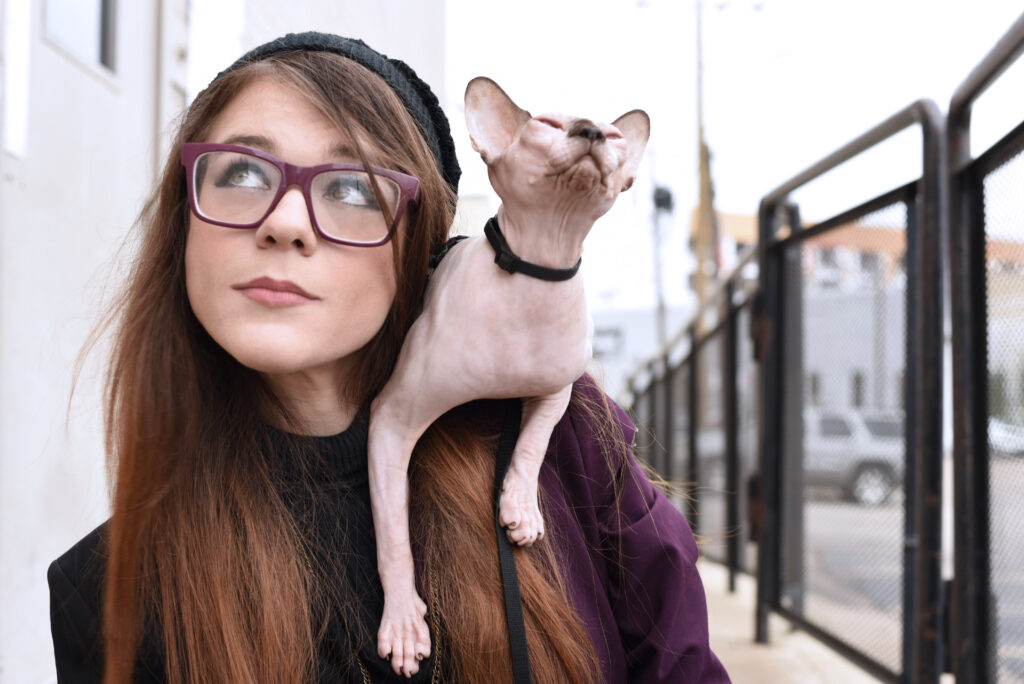 Picture of voice actor Krystal Laporte with Atticus the Sphinx cat on her shoulder.
